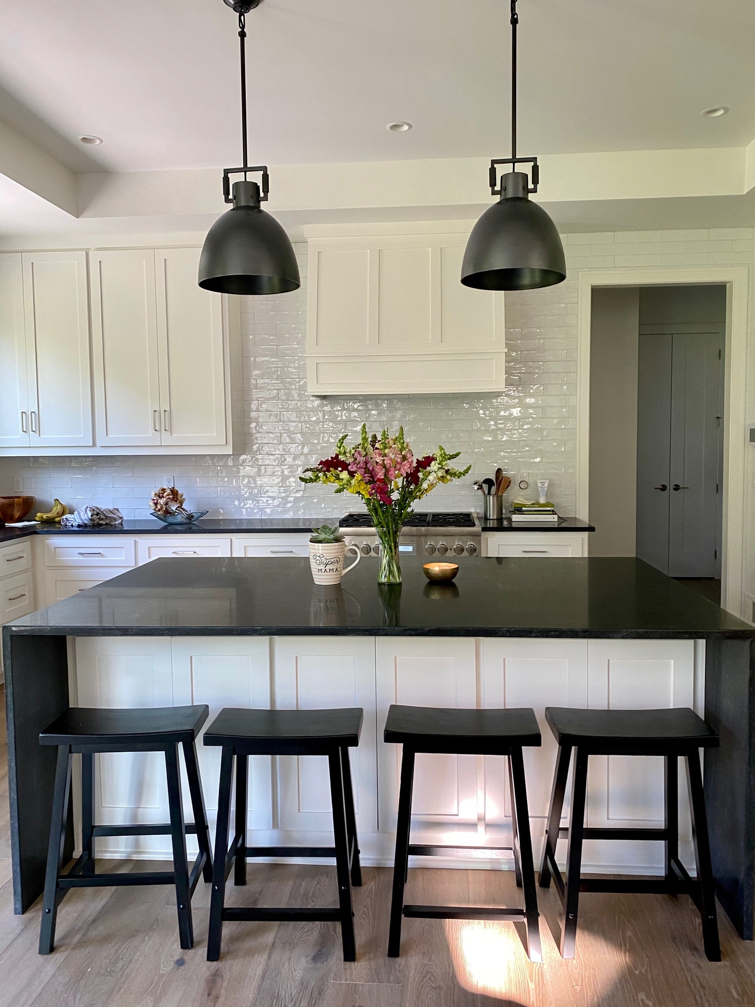 A clean farmhouse style kitchen and island with two metal pendant lights.